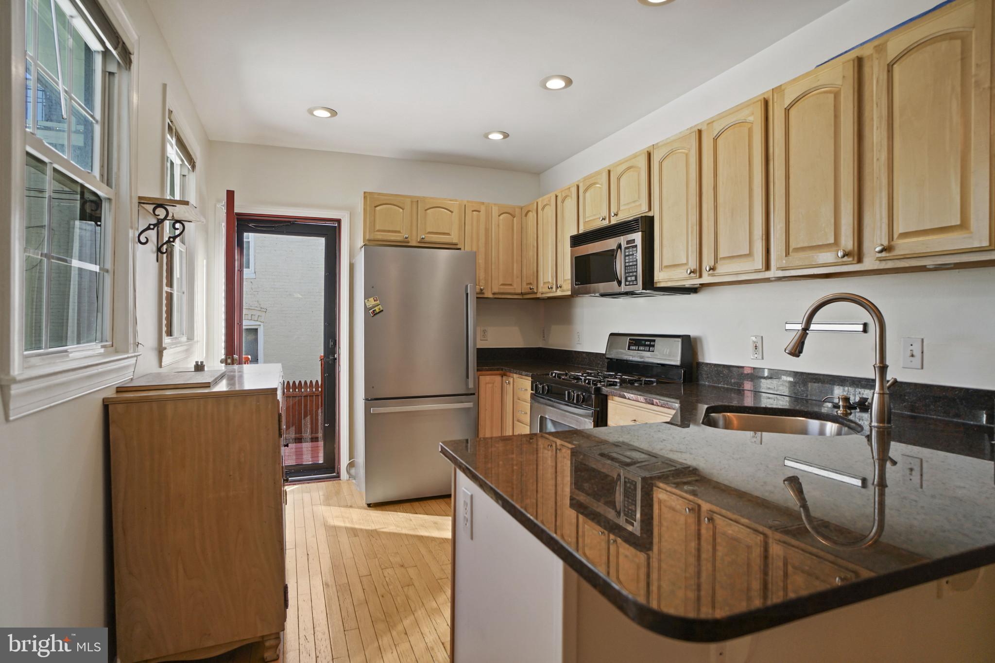 1417 Covington Street Baltimore, MD 21230 - Photo 8 of 25 a kitchen with stainless steel appliances granite countertop a sink a stove and a refrigerator with wooden cabinets