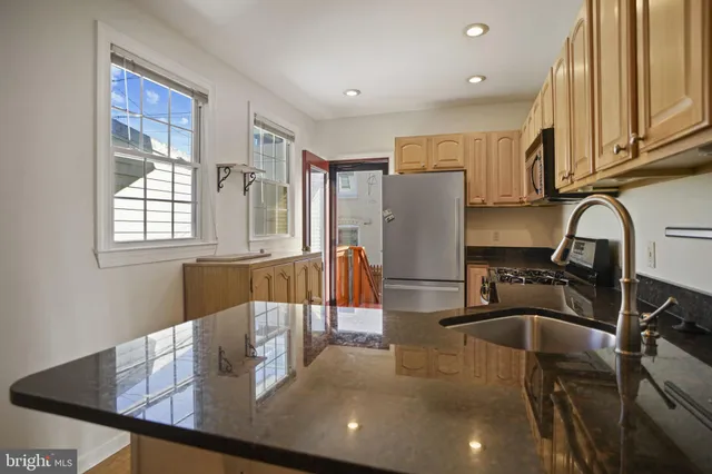 a kitchen with stainless steel appliances granite countertop a sink refrigerator and cabinets