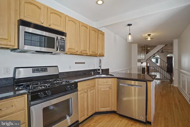 a kitchen with granite countertop a sink cabinets and stainless steel appliances