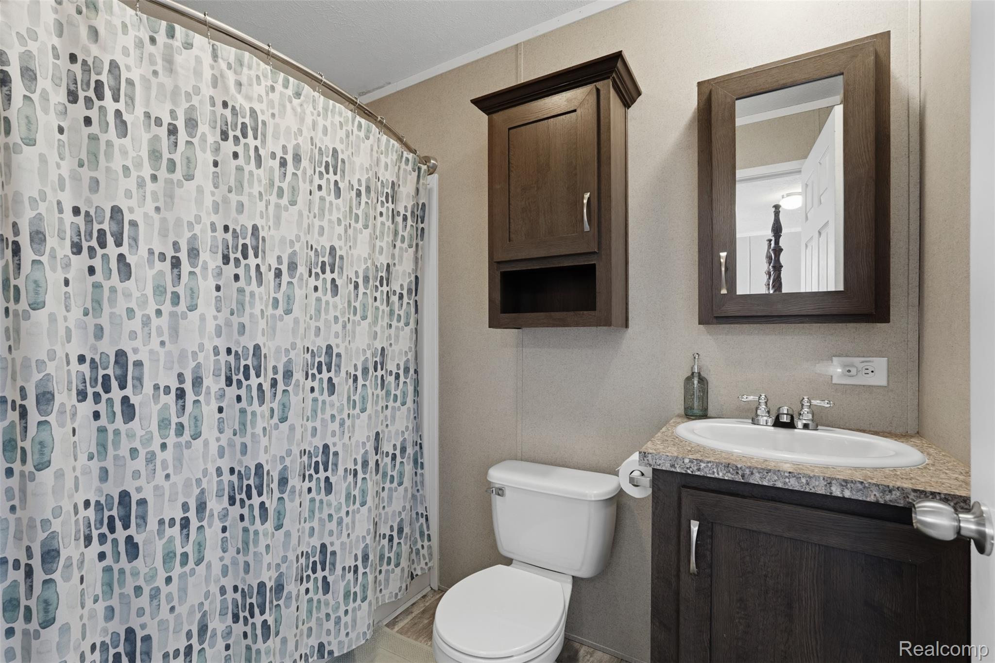 92 Normandy Drive Howell, MI 48843 - Photo 13 of 24 Bathroom featuring a vanity with an integrated sink, a dark wood-finish cabinet, and a coordinating dark wood-finish medicine cabinet