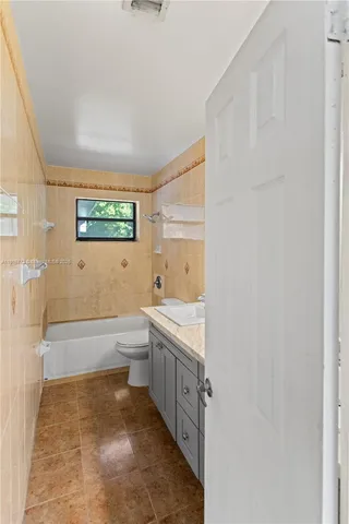a bathroom with a granite countertop sink a toilet and bathtub