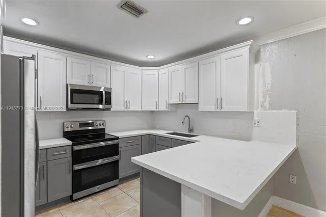 a kitchen with stainless steel appliances a stove a sink a refrigerator and white cabinets