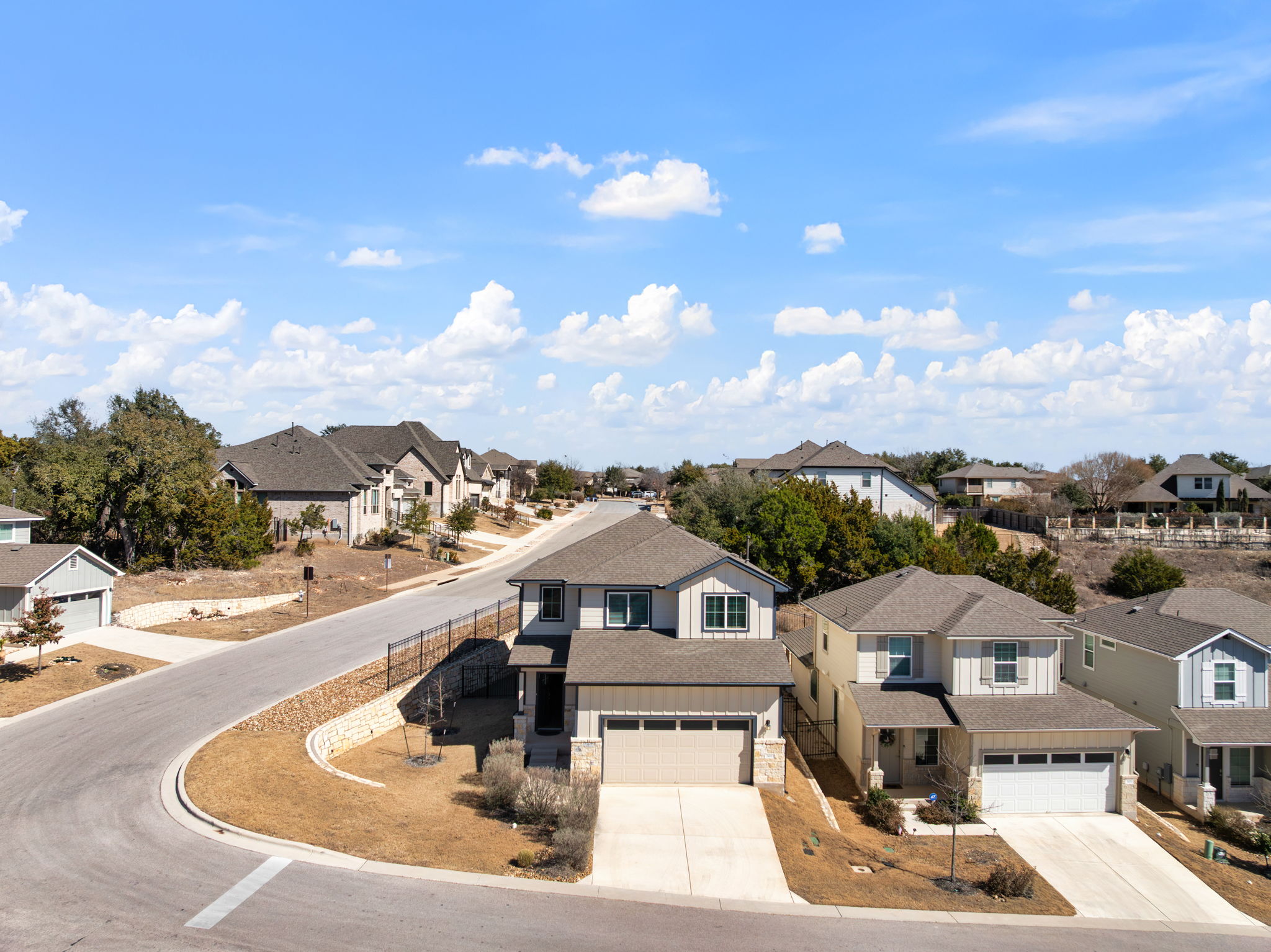101 Merrick Road Georgetown, TX 78628 - Photo 32 of 38 View of front facade featuring concrete driveway, a residential view, a garage, stone siding, and a shingled roof