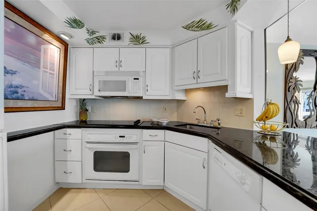 a kitchen with granite countertop white cabinets and white appliances