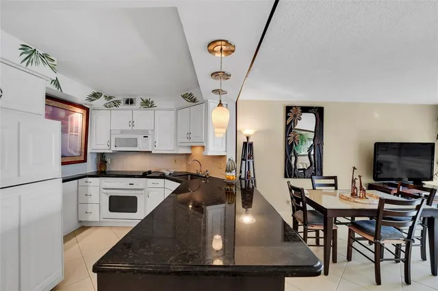 a view of a kitchen with kitchen island a stove a microwave a dining table and chairs with wooden floor