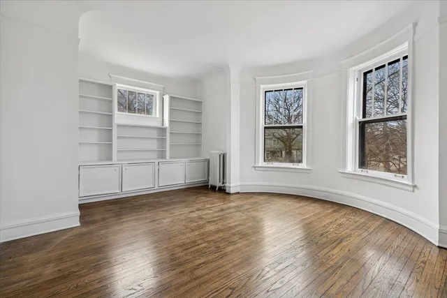 a view of an empty room with a window and wooden floor