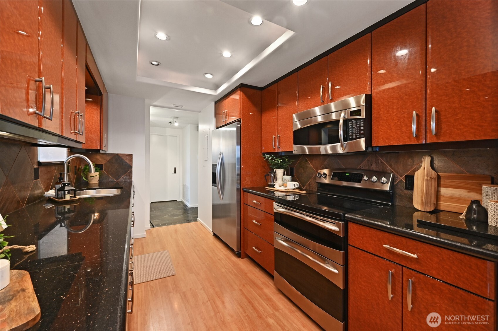 1301 Spring Street, Unit 10F Seattle, WA 98104 - Photo 9 of 36 a kitchen with stainless steel appliances wooden cabinets a stove and a refrigerator