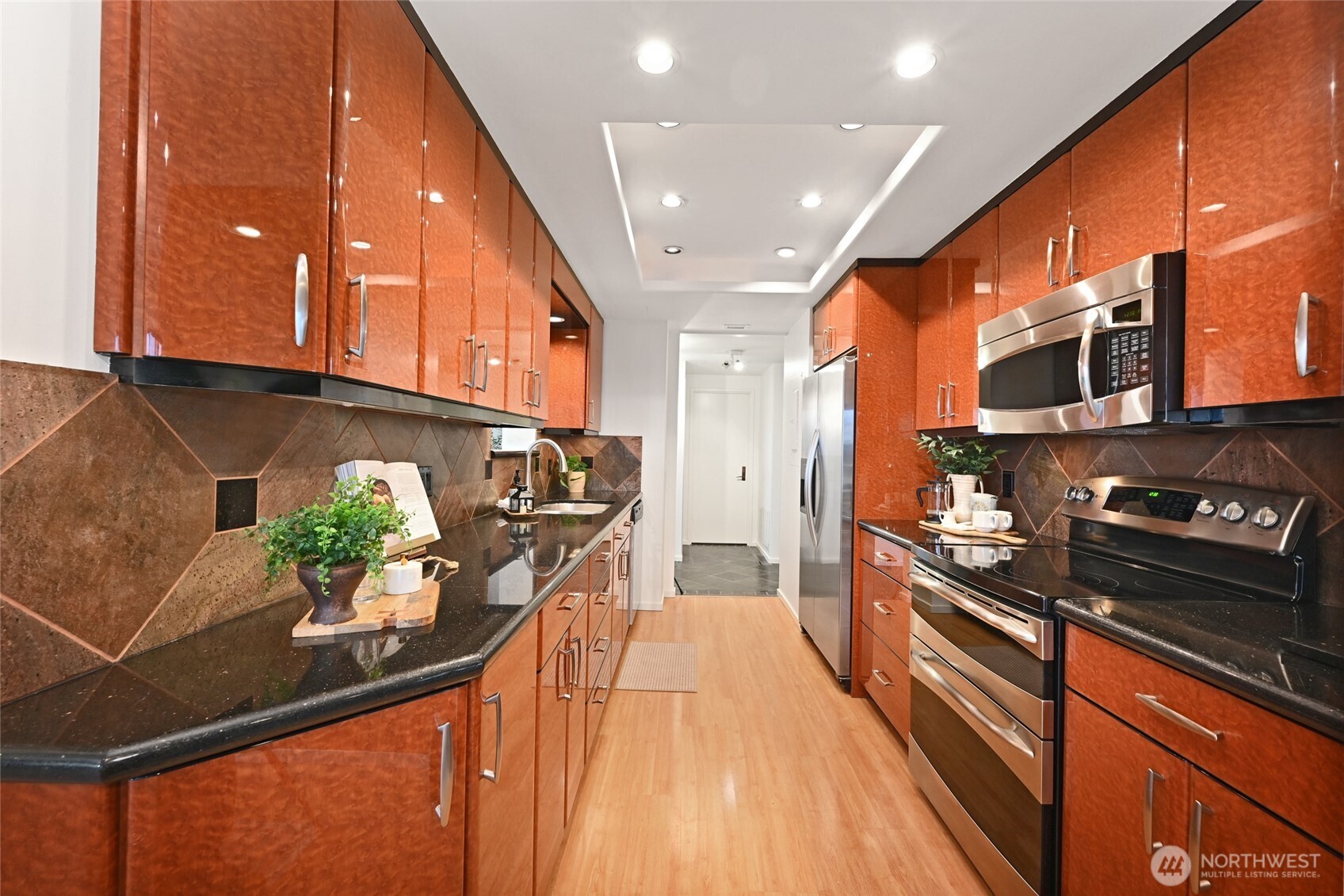 1301 Spring Street, Unit 10F Seattle, WA 98104 - Photo 10 of 36 a kitchen with stainless steel appliances kitchen island granite countertop a stove a sink and a microwave