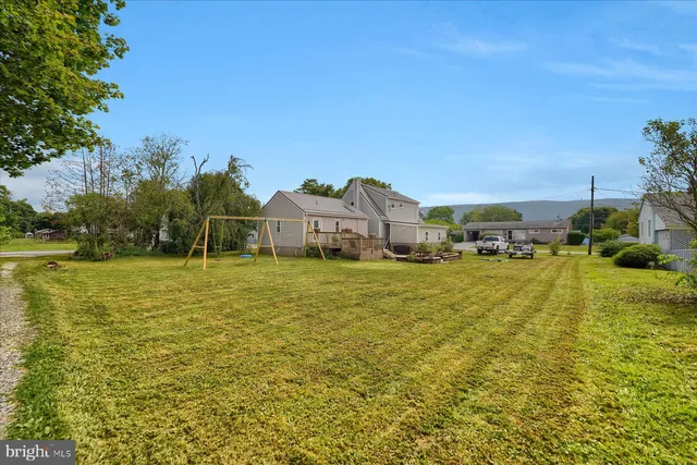 a view of a house with backyard and trees in the background