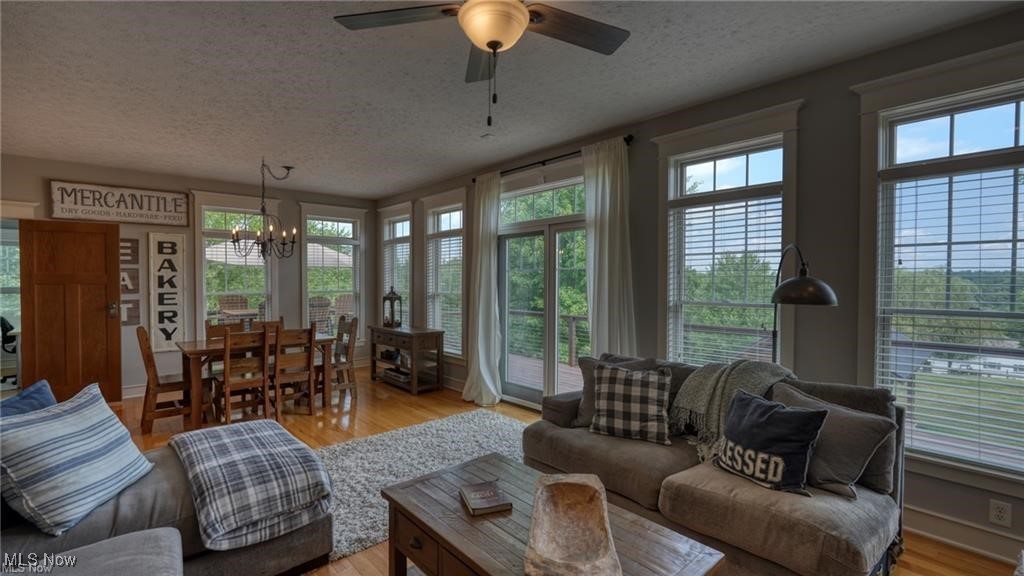 66333 Read Road Cambridge, OH 43725 - Photo 23 of 49 Living room with ceiling fan with notable chandelier, a textured ceiling, and light hardwood / wood-style flooring