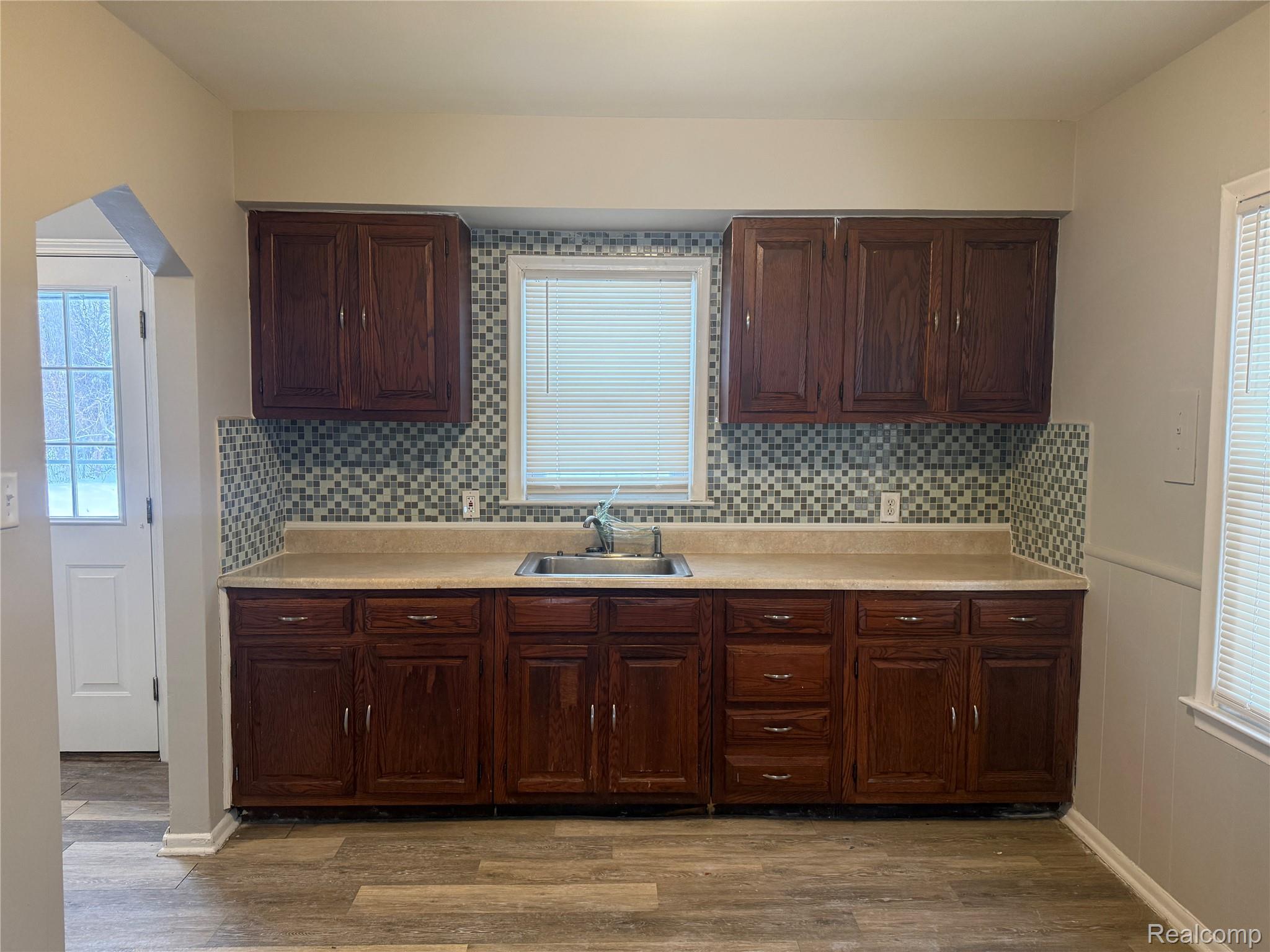 6237 Inkster Road Taylor, MI 48180 - Photo 5 of 14 Wood-finish flooring with dark wood cabinetry, a mosaic tile backsplash, and light-toned countertops