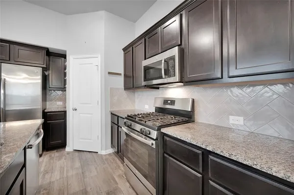 a kitchen with stainless steel appliances granite countertop a stove a refrigerator and a microwave