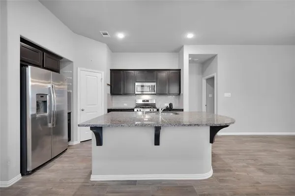 a view of a kitchen with stainless steel appliances granite countertop a sink and a refrigerator