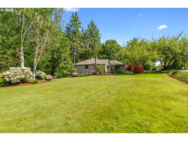 a view of a yard with flower plants and wooden fence