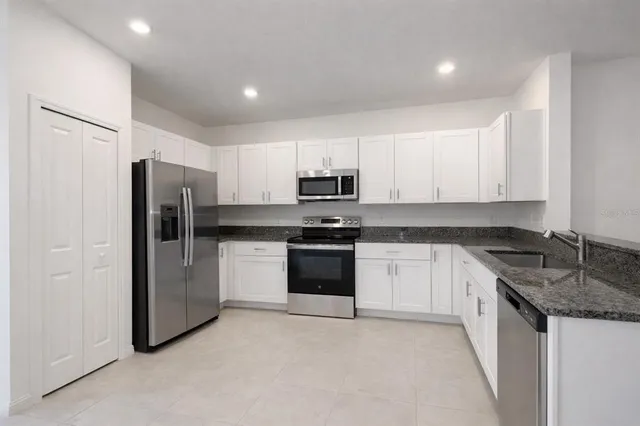 a kitchen with granite countertop white cabinets and refrigerator