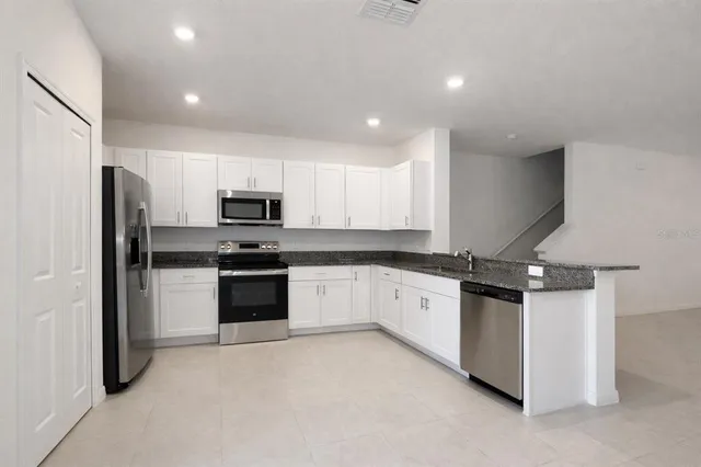 a kitchen with granite countertop white cabinets and stainless steel appliances