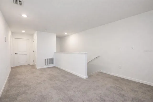 an empty room with a chandelier fan and windows
