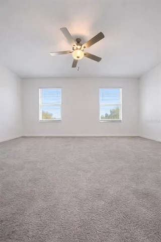 an empty room with windows and fan