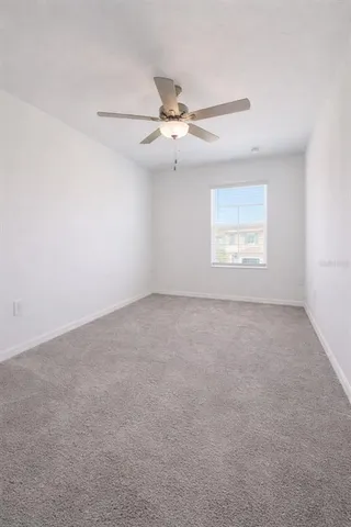 an empty room with a window and a fan