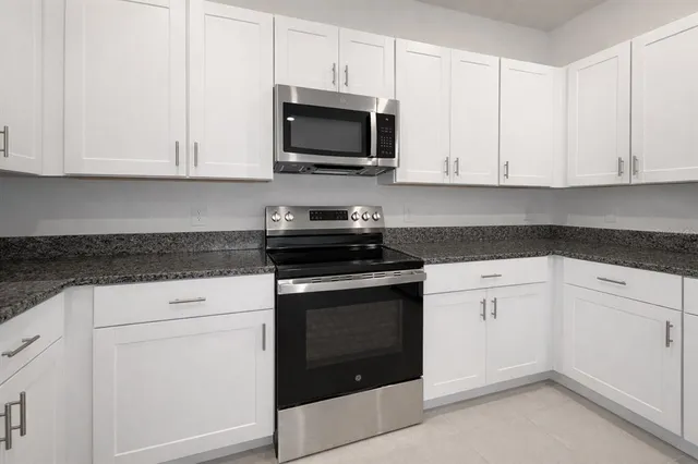 a kitchen with white cabinets and black appliances