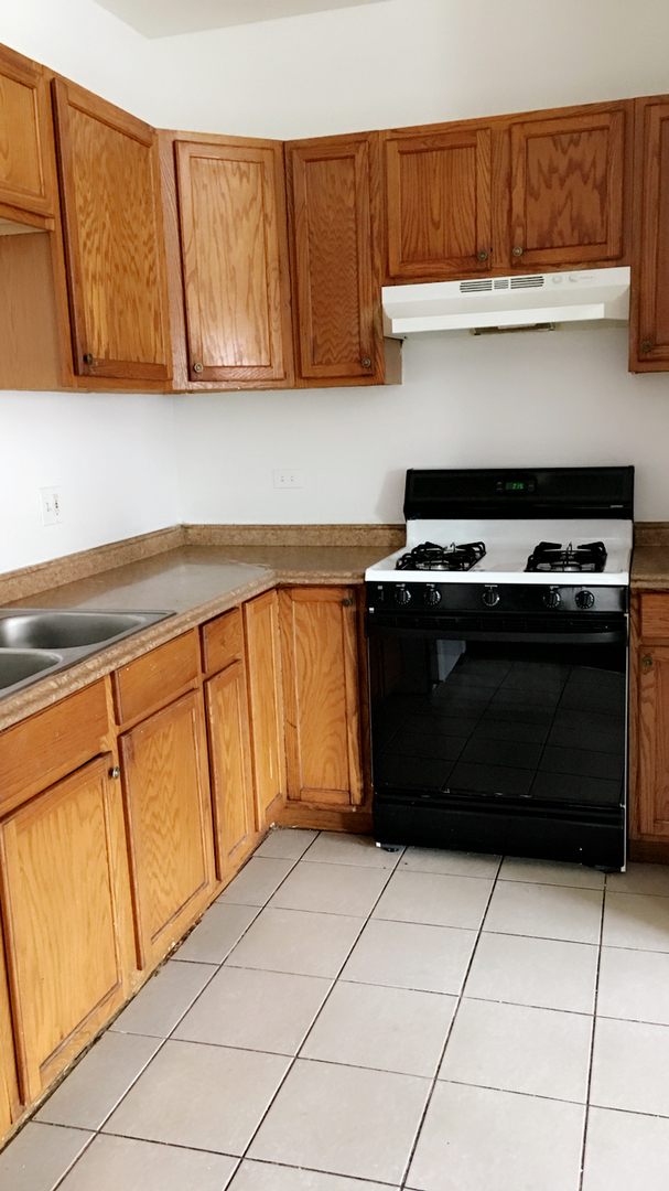 3636 West Cermak Road, Unit 2F Chicago, IL 60623 - Photo 3 of 5 a kitchen with a cabinets and a stove top oven