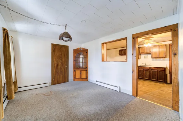 a view of an empty room and bathroom with wooden floor and a window
