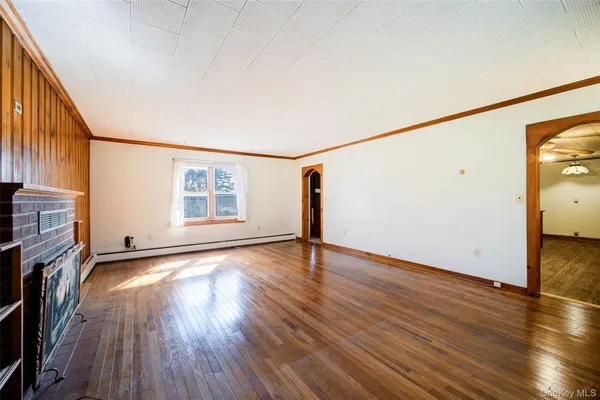 a view of an empty room with a window and wooden floor