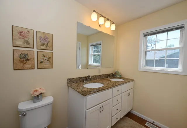 a bathroom with a granite countertop sink toilet and a window