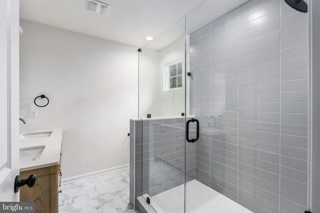 a view of a hallway with wooden floor and a bathroom