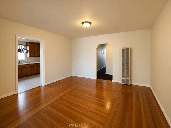a view of a livingroom with wooden floor and kitchen