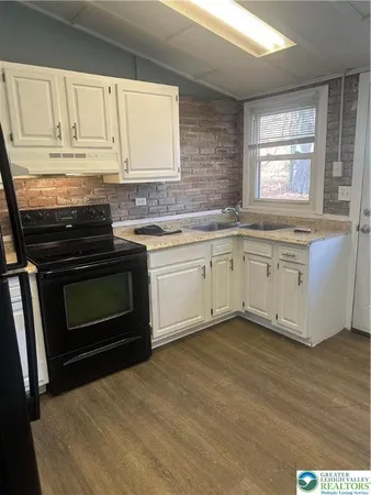 a kitchen with granite countertop a stove sink and cabinets