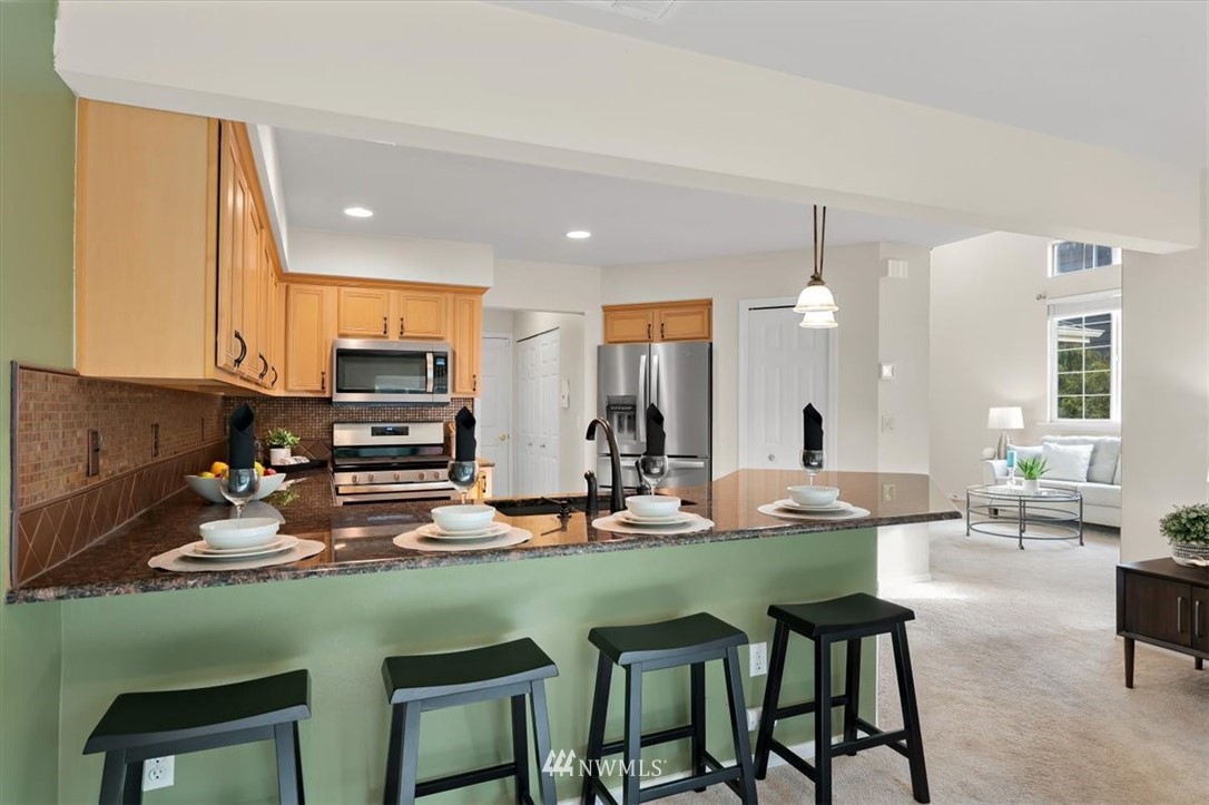 18346 Rainier View Road Southeast Monroe, WA 98272 - Photo 10 of 40 a kitchen with stainless steel appliances a table and chairs in it