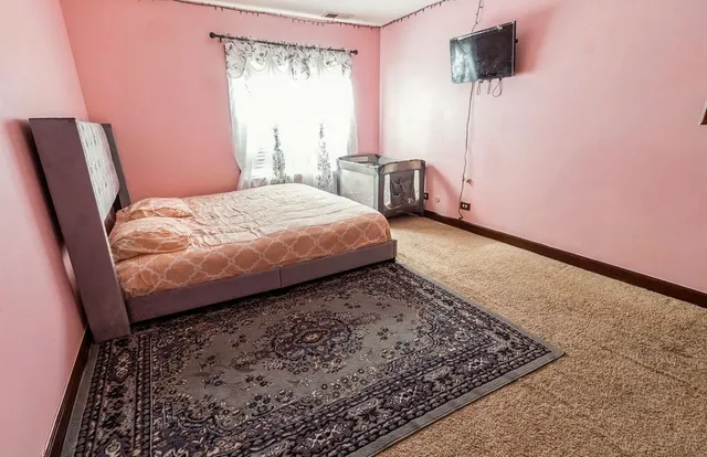 a bed sitting in a bedroom next to a window with a chair