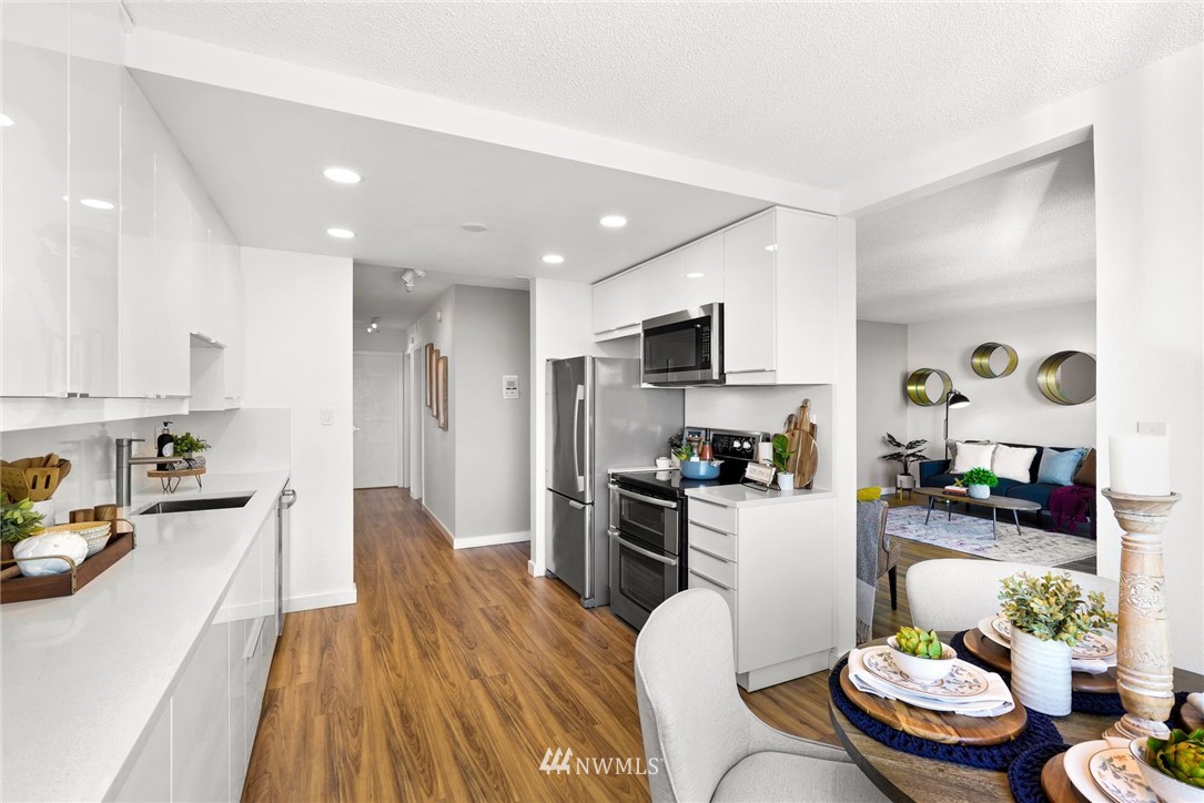 507 West Mercer Street, Unit 603 Seattle, WA 98119 - Photo 8 of 21 a kitchen with stainless steel appliances kitchen island granite countertop a refrigerator a sink a stove and white cabinets