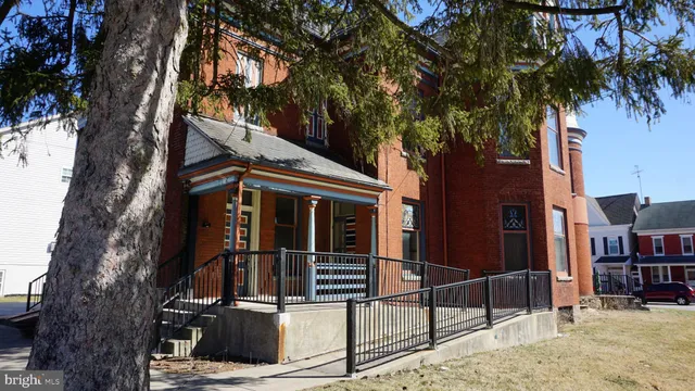 a view of a house with large tree and wooden fence