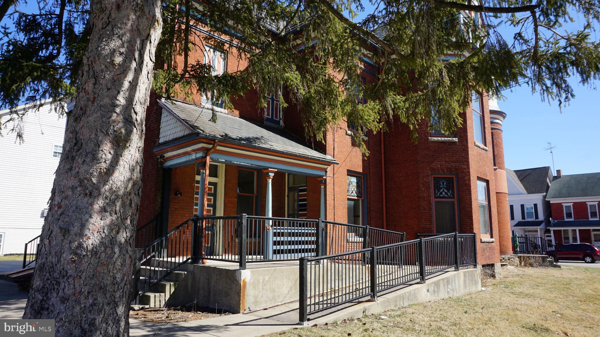 a view of a house with large tree and wooden fence