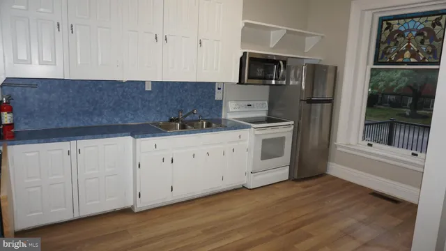 a kitchen with stainless steel appliances granite countertop a stove a sink and white cabinets