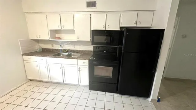 a kitchen with a sink a refrigerator and cabinets