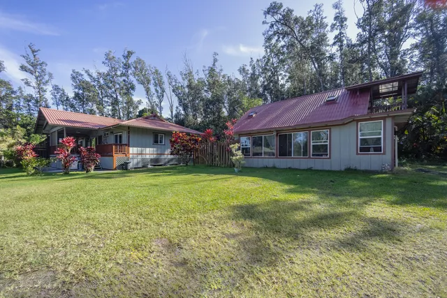 a view of a big house with a big yard plants and large trees