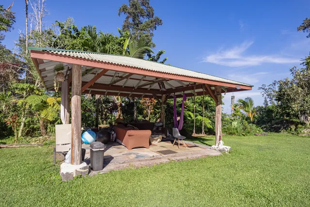 a view of a patio with a table and chairs under an umbrella with a small yard