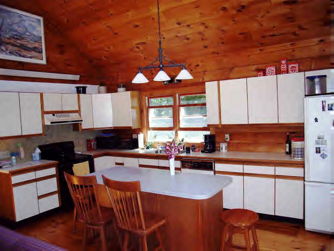 196 Woodmere Road Becket, MA 01223 - Photo 2 of 6 a kitchen with stainless steel appliances a dining table chairs sink and wooden floor
