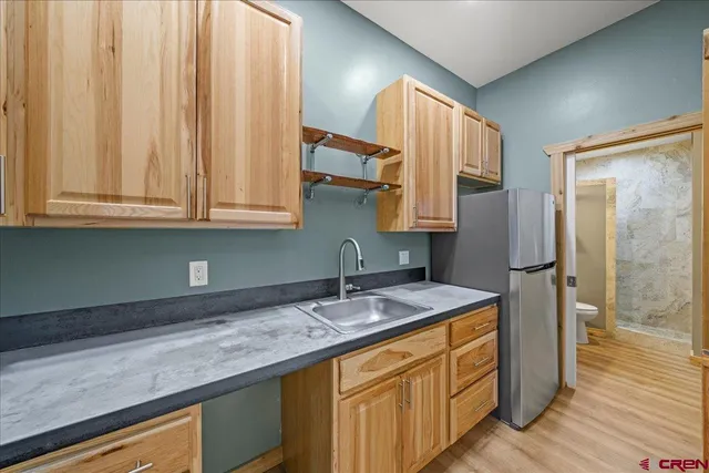 a kitchen with stainless steel appliances granite countertop a sink a refrigerator and a wooden cabinets