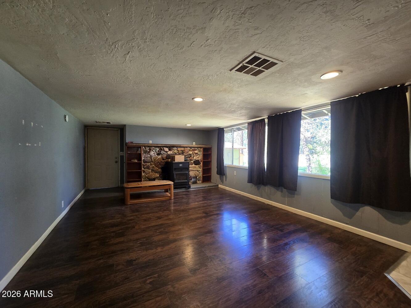 118 East Frontier Street Payson, AZ 85541 - Photo 4 of 22 an empty room with windows fireplace and wooden floor