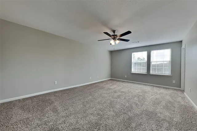 an empty room with windows and fan