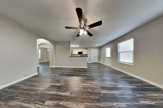 a view of an empty room with window and wooden floor