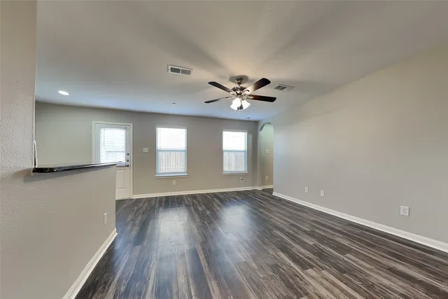 a view of an empty room with a window and wooden floor