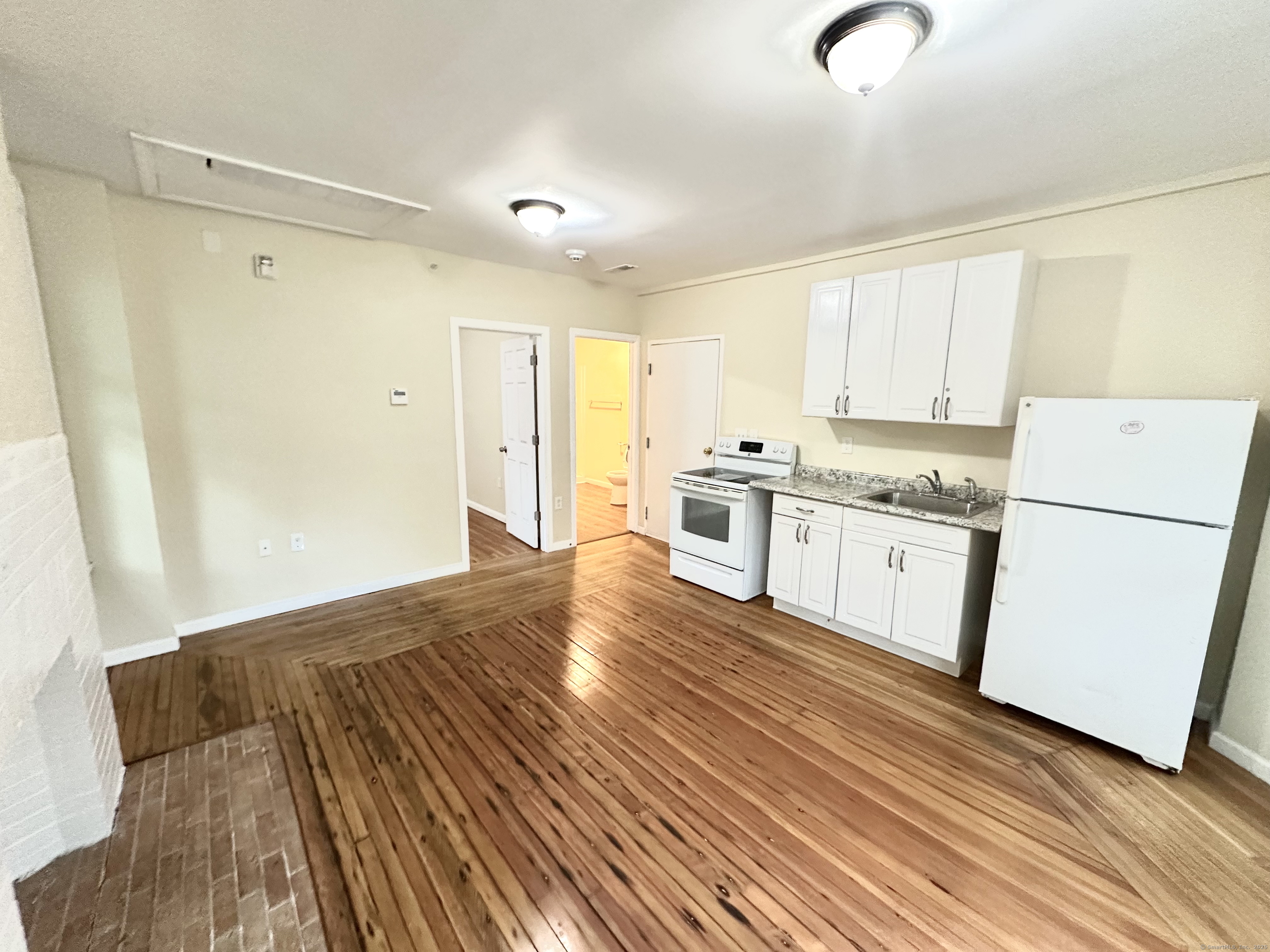 a kitchen with granite countertop white cabinets and white appliances