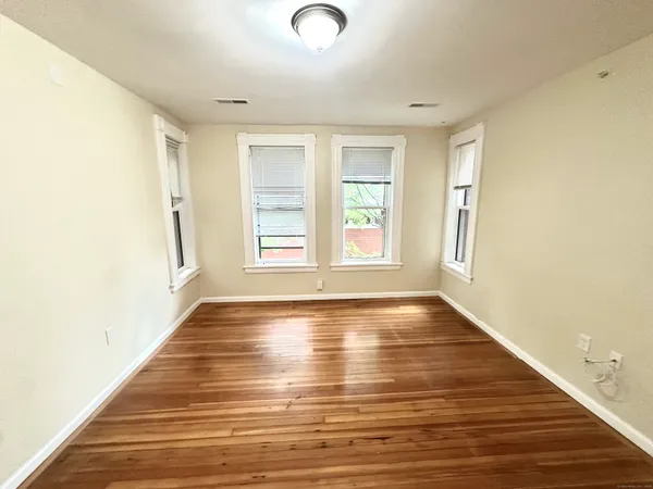 a view of an empty room with wooden floor and a window