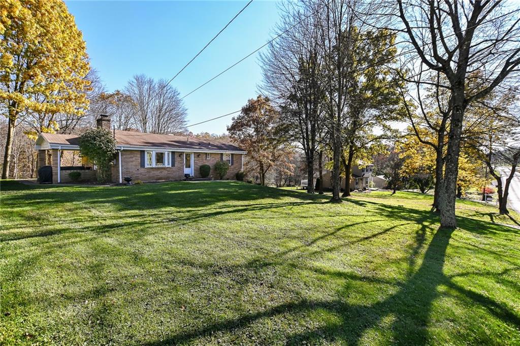 a view of a house with big yard and large trees