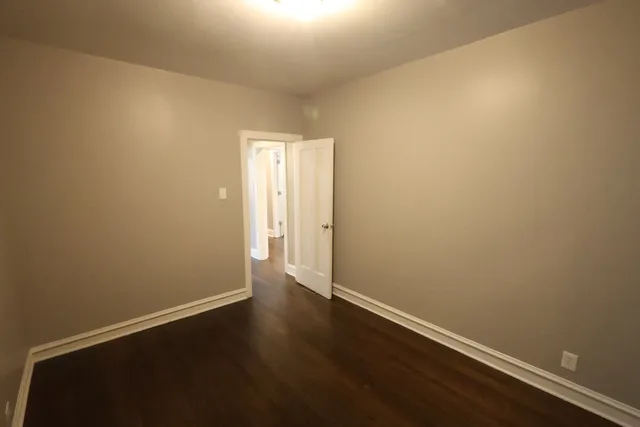 an empty room with wooden floor and white wall